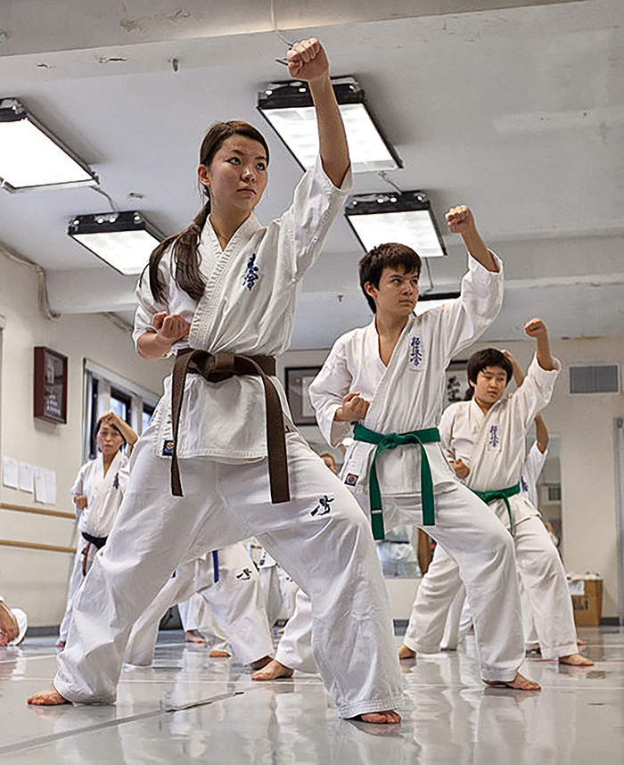 Kids in white gi practising kicks with an instructor at the KKNY dojo
